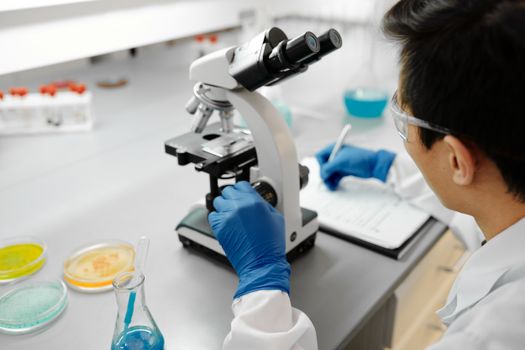 Scientist using a microscope to analyze samples in a modern laboratory environment.